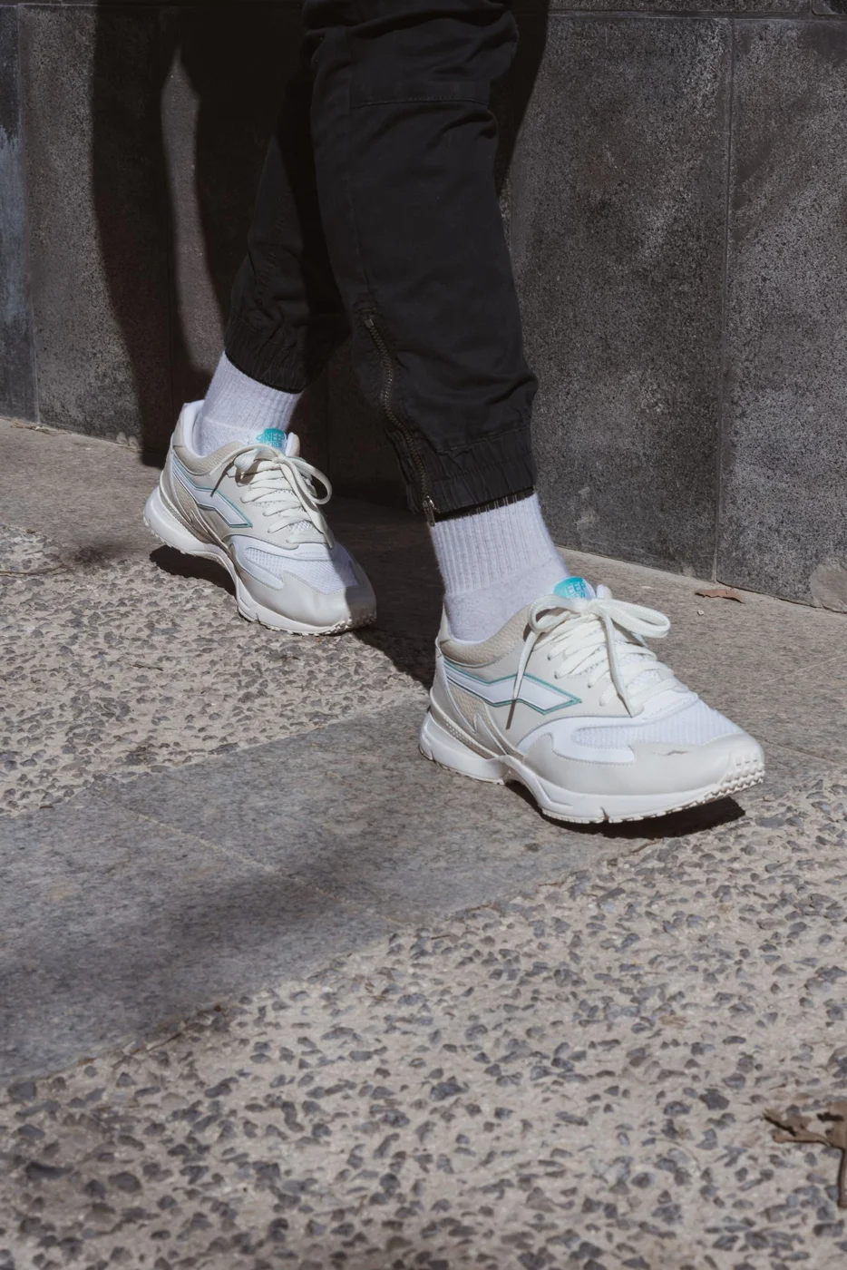 White walking sneakers and socks on textured city pavement