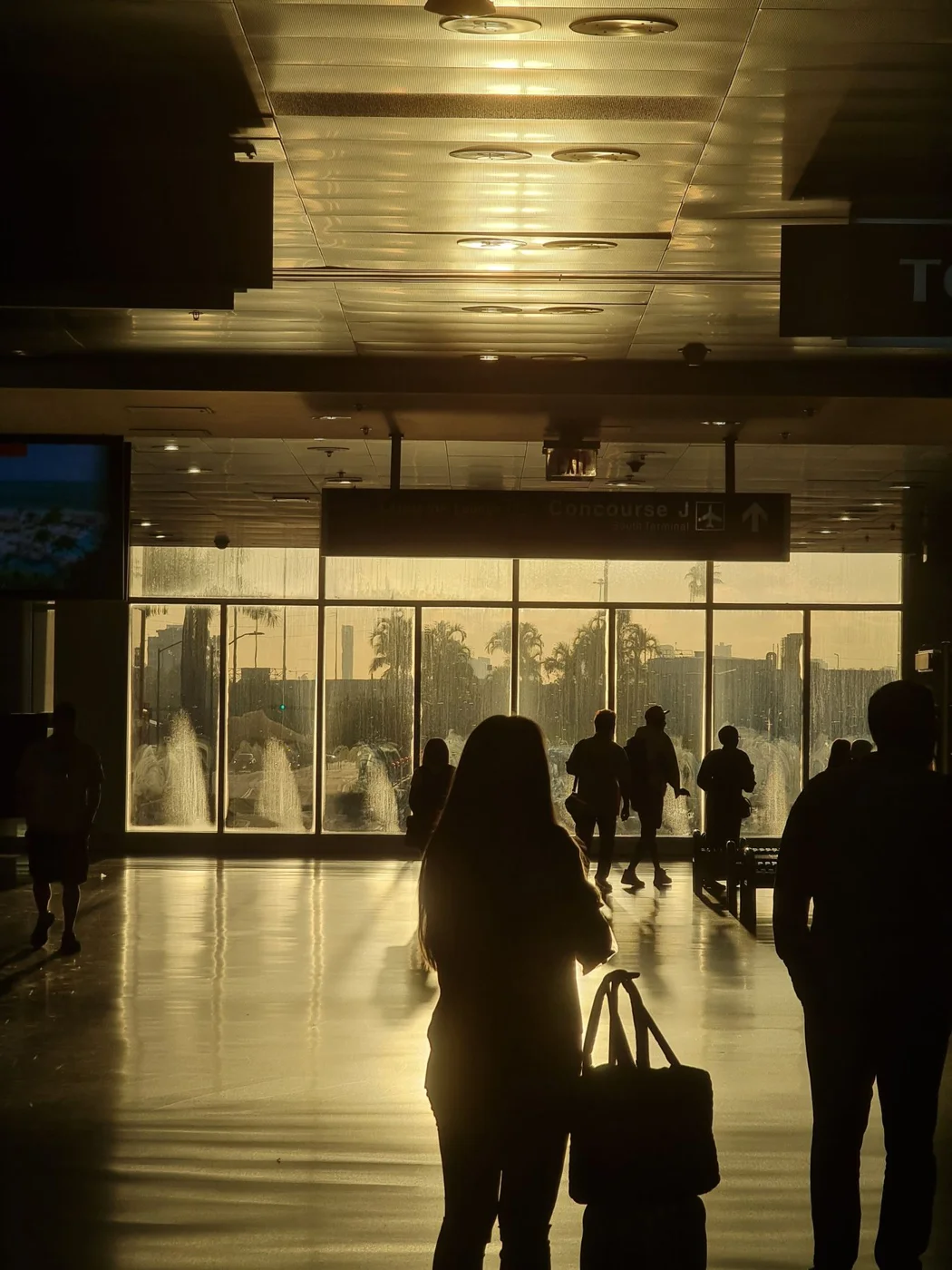 Travelers moving through a sunlit terminal at Miami airport